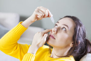 young woman applying eye drop