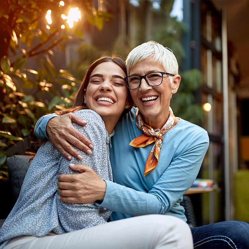 mom and daughter hugging and laughing together outside