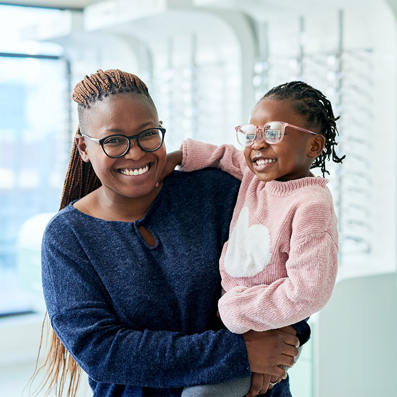 mother and young daughter trying on glasses at the eye doctor