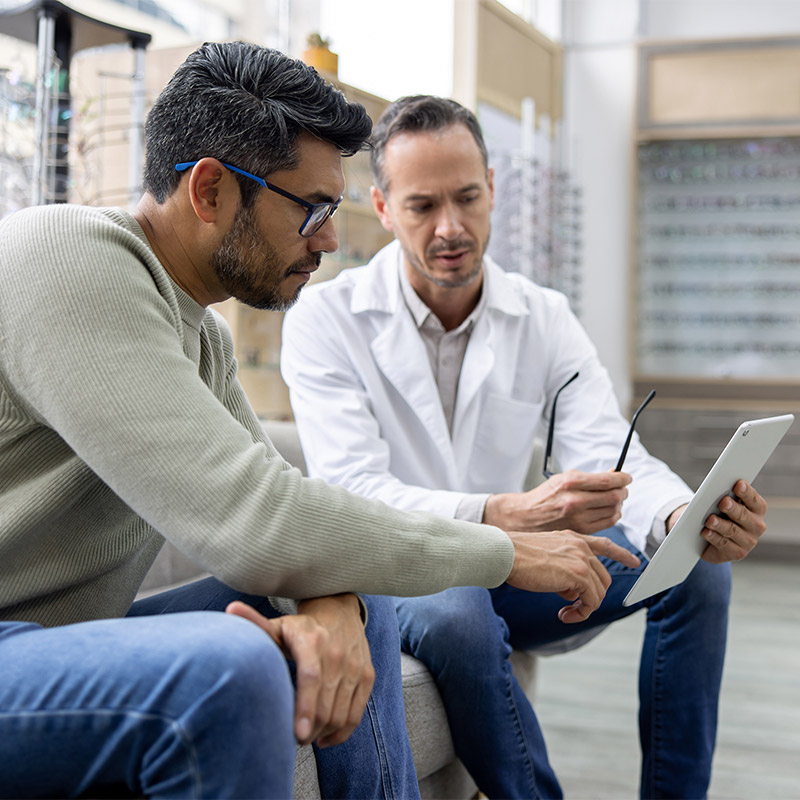optometrist talking with client and looking at a smart device