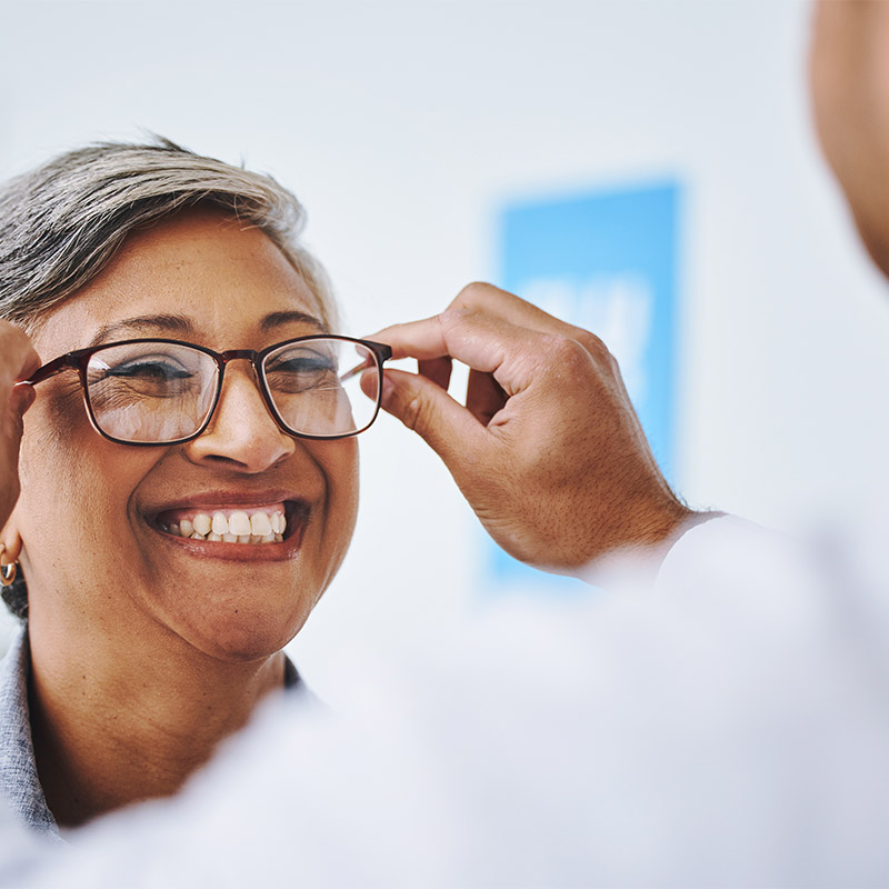 woman trying on glasses at eye doctor appointment