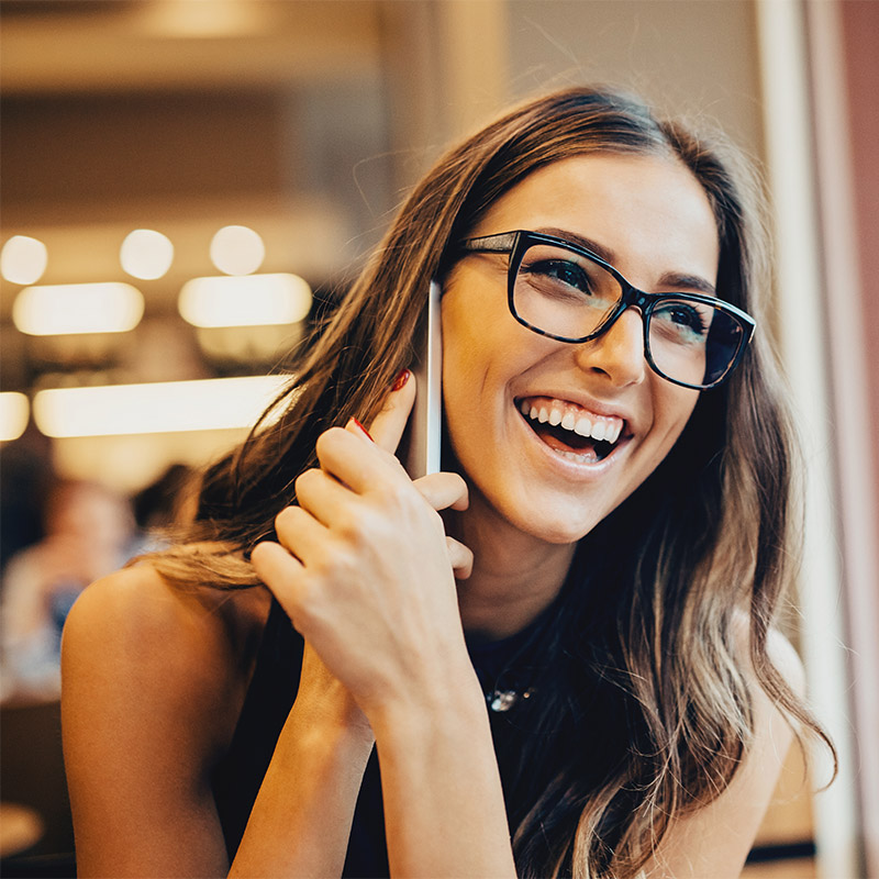 woman smiling with holding phone up to her ear