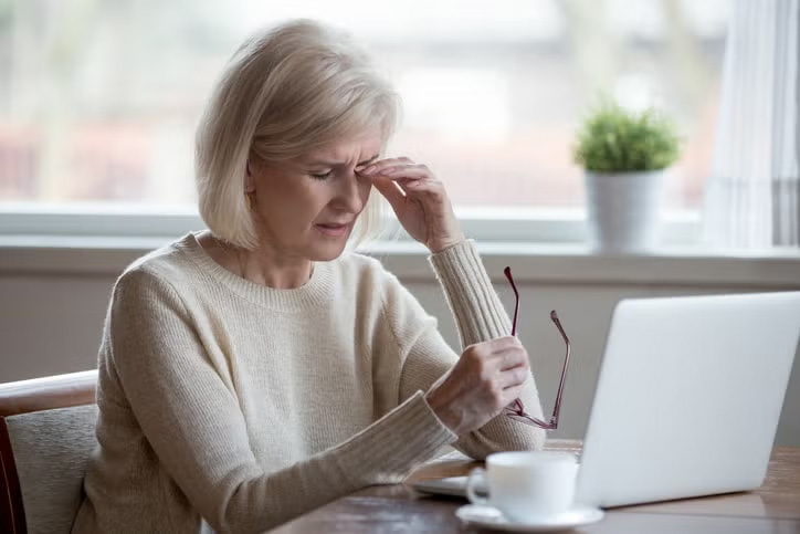 Grandma getting headache from looking at her laptop for long hours