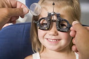 A smiling child undergoes an eye exam,