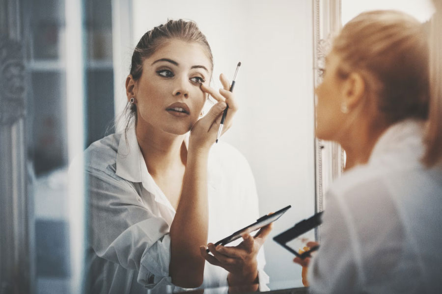 a woman applying makeup on her eyes