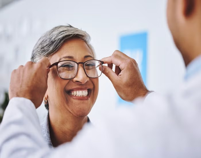 Aged women smiling while checking her eyeglasses