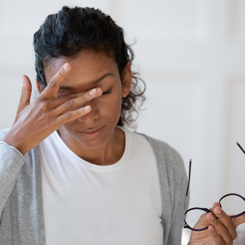 woman holding her glasses and rubbing her eye