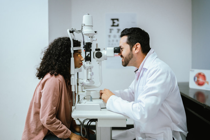 An optometrist conducting an eye examination using a slit lamp in a clinic in Derry, NH