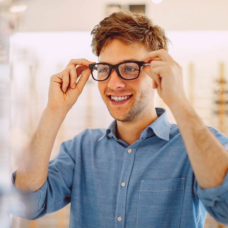 Man smiling while trying on glasses in a store in Derry, NH, and Nearby Areas